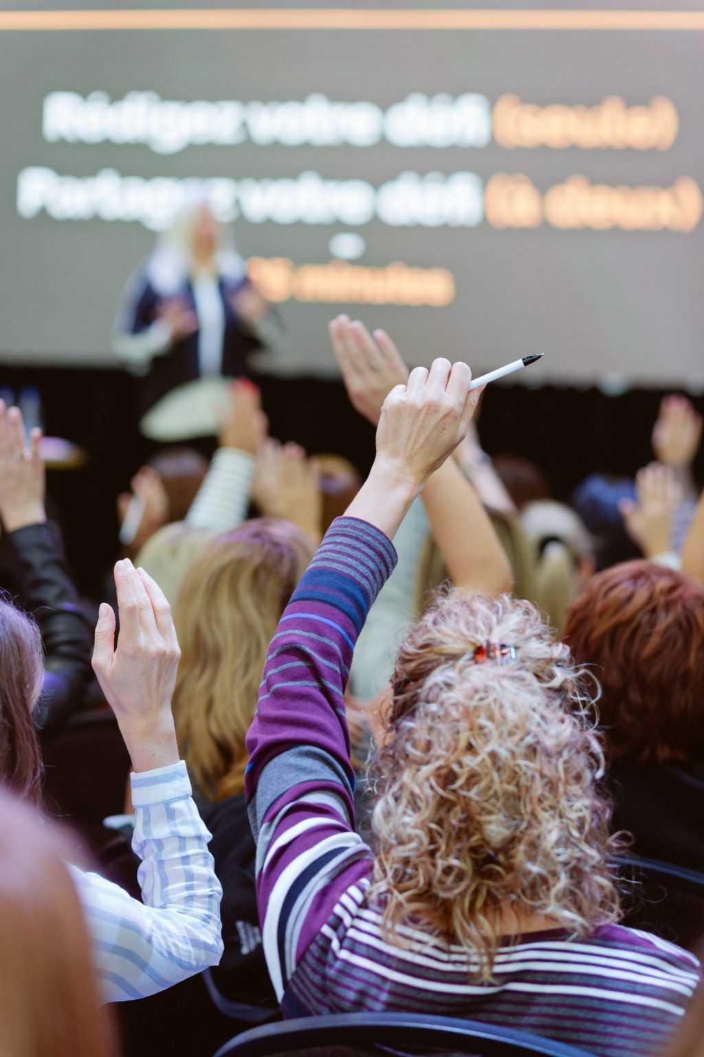 Femmes qui lèvent la main lors d'une conférence aux locaux L'effet A.