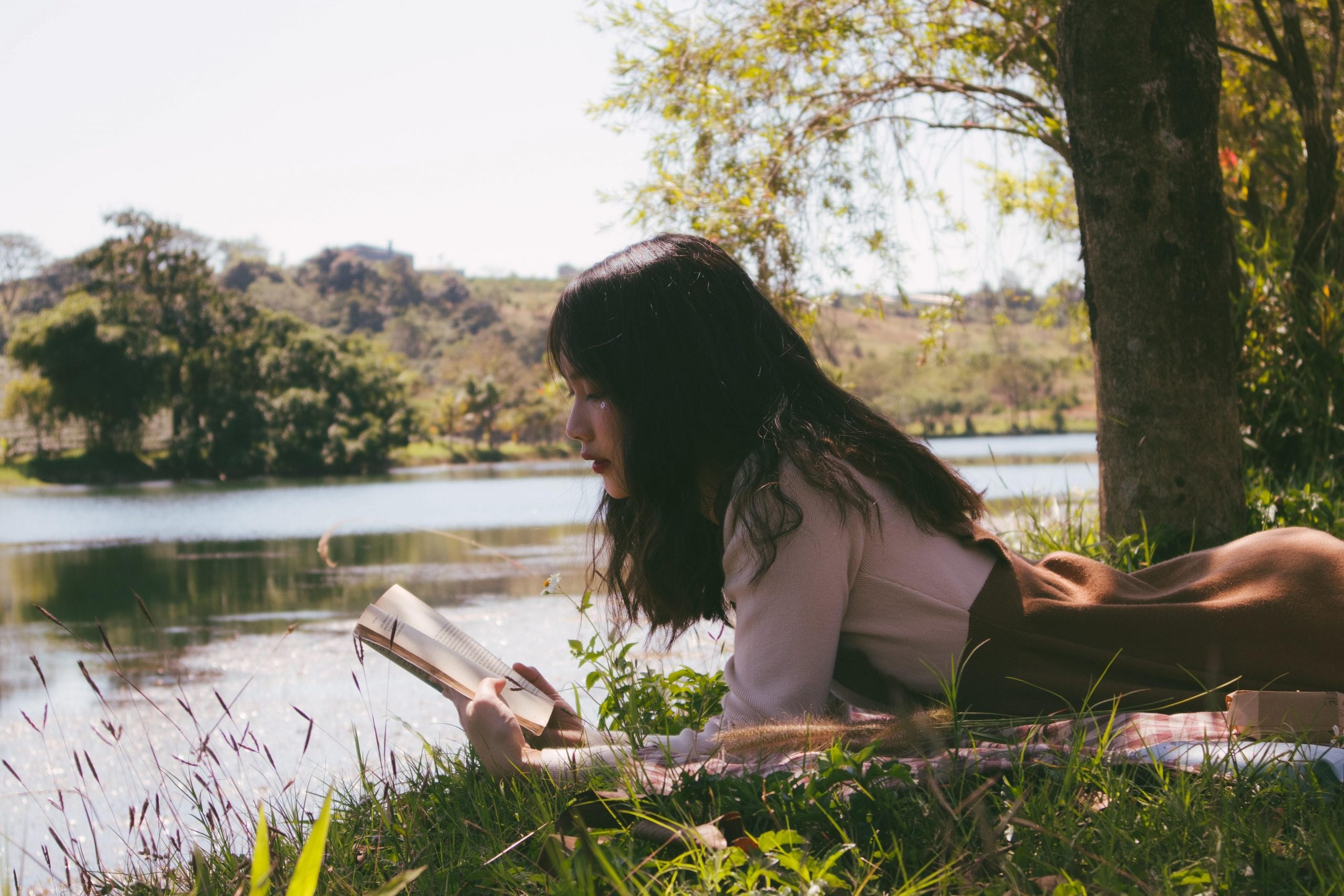 jeunne fille en bord de lac, lisant un livre